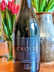 Bottle of Croix Estate wine positioned in vineyard setting, reflecting artisanal winemaking in Russian River Valley.